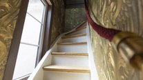Über den stilvollen Treppenaufgang gelangen Gäste in das einzigartige Turmzimmer des Schlössle Seeburg. Die elegante Wandgestaltung, das natürliche Licht und die historische Atmosphäre machen bereits den Weg nach oben zu einem Erlebnis.