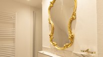 Elegante Waschbecken-Armatur im gold-weißen Bad der Suite Nachtigall im Schlössle Seeburg