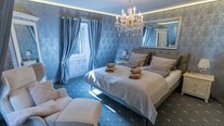 Stilvolles Doppelzimmer in Silber- und Grautönen mit Kronleuchter, großem Spiegel und hochwertiger Ausstattung.