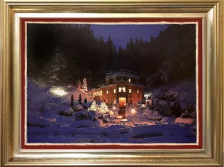 Winterliche Aufnahme des festlich beleuchteten Schlössle Seeburg mit verschneitem Garten und Waldkulisse bei Nacht.