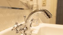 Elegante Waschbecken-Armatur im gold-weißen Bad der Suite Nachtigall im Schlössle Seeburg