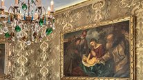 Edle Details prägen das Turmzimmer im Schlössle Seeburg: kunstvolle Tapeten, ein prachtvoller Kronleuchter und historische Gemälde schaffen ein einzigartiges Ambiente voller Eleganz und Charme.
