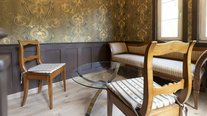Gemütliche Sitzecke im Turmzimmer mit historischen Möbeln, eleganten Tapeten und besonderem Ambiente zum Entspannen.