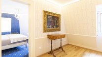 Kleiner Salon der Suite Nachtigall im Schloss Seeburg mit historischem Gemälde, antikem Tisch und Blick ins Schlafzimmer.